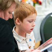 Young boy reading magazine with lady